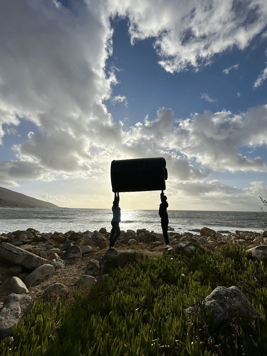 Two people lifting a Makulu tank overhead on the coast