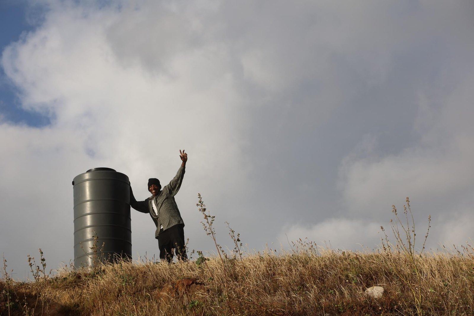 A man waving beside a Makulu tank on a grassy hill